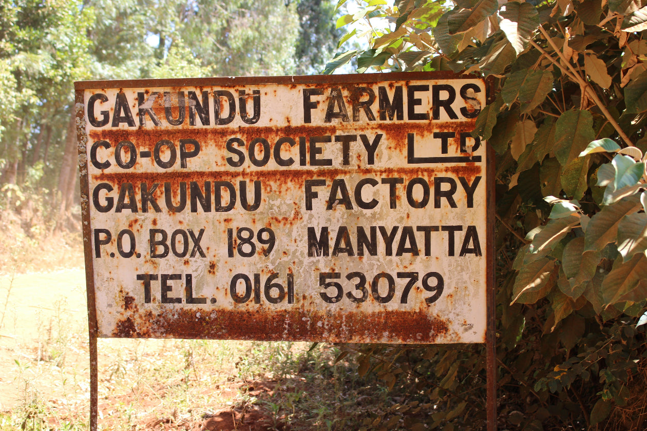 Rust-colored sign for Gakundu Farmers Co-op Society Ltd with contact information.